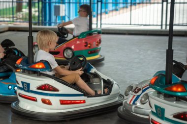 Go kart yarışında çocuk parkında eğlenen genç sürücüler. Lunaparkta çarpışan araba kullanan çocuklar.