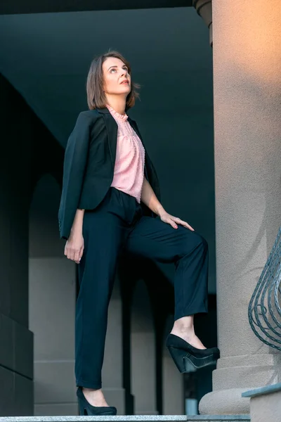 Tired business woman rests on the street. Middle-aged woman in trousers and jacket