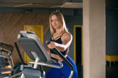 Aerobik sınıfındaki zinde kız. Modern spor salonunda spor yapan bir bayan. Boş spor salonunda koşan zayıf vücutlu seksi kaslı kadın.