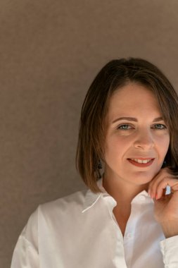 Beyaz gömlekli, gülümseyen orta yaşlı kadın. Portreyi kapat. Resmi giyinmiş bir iş kadını.