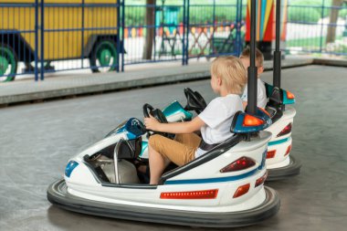 Sarışın çocuk lunaparkta elektrikli araba kullanıyor. Mutlu bir çocukluk. Tema parkı. Çarpışan araba.