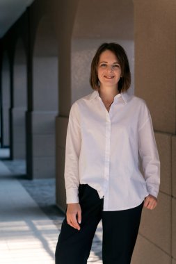 Ofis merkezinde beyaz gömlekli başarılı genç bir kadın. Gülümseyen iş kadını