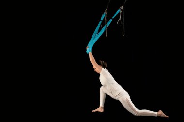 Genç bir kadın salıncakta salıncak sallıyor. Arkayı geriyorum. Yan görünüm siyah arkaplanda izole edildi