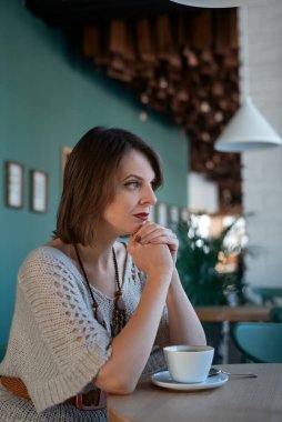 Restoranda çay ya da kahve içen güzel genç kadınlar. Esmer kadın portresi, sert bakışlı.