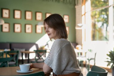 Genç bir kadın kafede kahve içerek eğleniyor. Rahat kafeteryadaki kızın portresi.