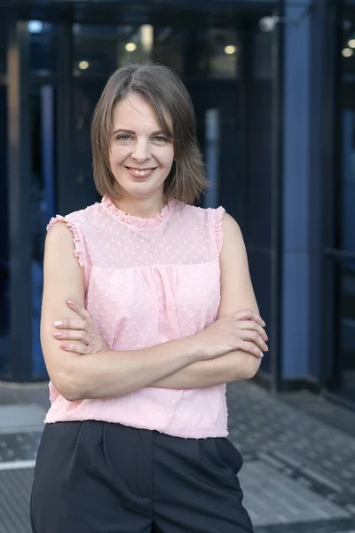 Smiling woman in pink blouse with bob haircut outside. Portrait of middle-aged woman