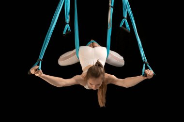 Kadın hamak kullanarak yoga yapıyor, sırt kaslarını geriyor, ters dönmüş Asana. Trapez sınıfındaki kız jimnastikçi. Siyah arkaplan