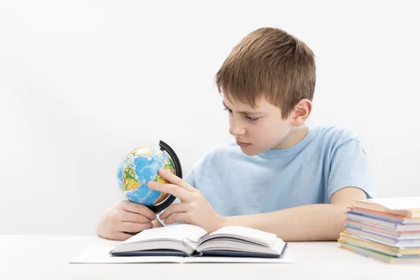 Serious Little Schoolboy Globe Copybooks Desk White Background Boy Studying — Fotografia de Stock