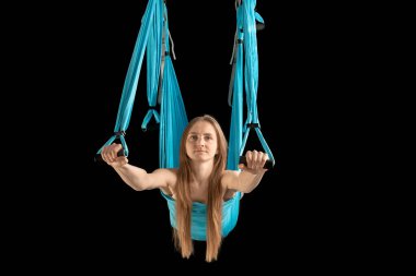 Athletic woman with healthy body performs exercises in sports hammock. Portrait of girl practicing fly yoga