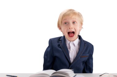 Schoolboy fools around while doing homework. Blond boy in school uniform makes grimaces. Screaming fidget boy. Isolated on white background