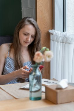 Woman sits at table in cafe, using the phone. Business woman on break in a cafe. Chatting in messengers.