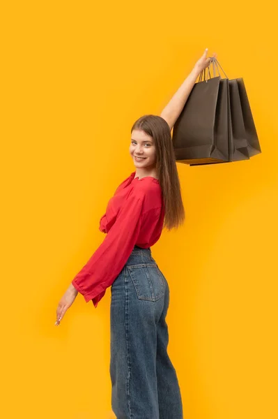 Smiling Young Woman Black Shopping Bag Her Hands Yellow Background — Zdjęcie stockowe