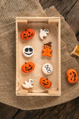 Masadaki ahşap tepside Cadılar Bayramı dekoru. Balkabağı şeklinde turuncu zencefilli kurabiye. Cadılar Bayramı için kurabiye. Üst görünüm