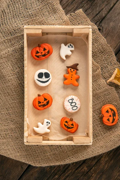 Halloween decor on wooden tray on the table. Orange ginger cookies in pumpkin shape. Cookies for Halloween . Top view