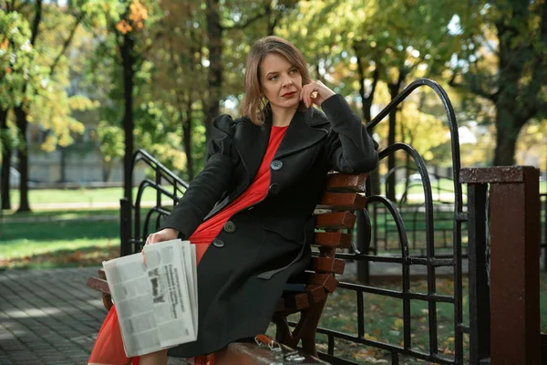 Mulher Meia Idade Pensive Senta Banco Parque Outono Com Jornal — Fotografia de Stock