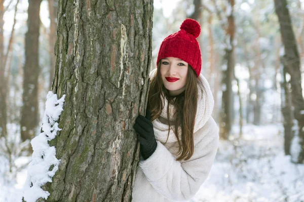 冬の森の中の赤い帽子のブルネットの女の子の肖像 — ストック写真