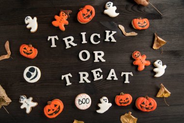 Cadılar Bayramı beyaz ve turuncu lezzetli zencefilli kurabiyeler kahverengi ahşap bir yüzey üzerinde yer alır. Yazı: şaka mı şeker mi.