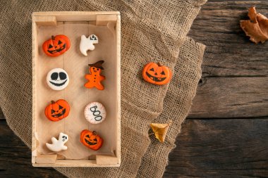 Balkabağı şeklinde turuncu zencefilli kurabiyeler. Masadaki ahşap tepside Cadılar Bayramı süsü. Cadılar Bayramı için kurabiye. Üst görünüm