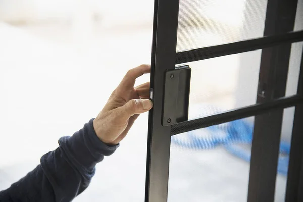 Man doing aluminum frame with glasses and wire screen door and window installation work in construction site