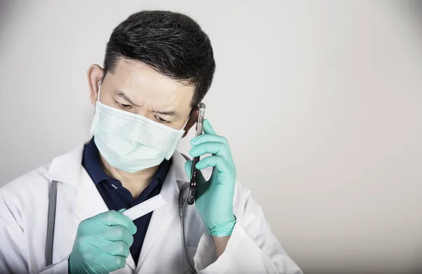 Asian Doctor Seriously Using Telephone While Checking Covid Virus Antigen — Stockfoto