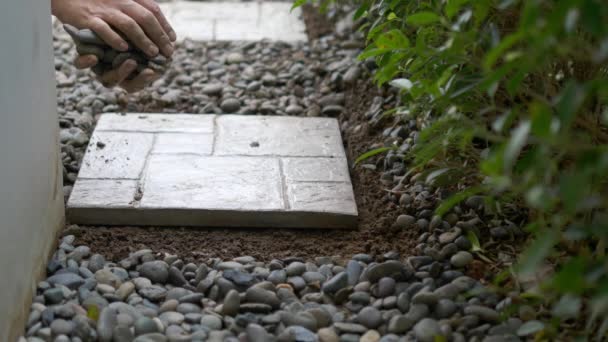 庭師はコンクリートスラブと石の材料を使用して自宅の庭の床の装飾で作業しています — ストック動画