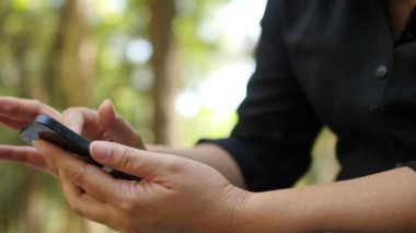 Yeşil bahçe arka planında cep telefonu kullanan bayan.