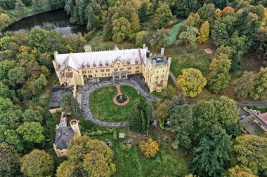 Nectiny Şatosu 'nun sarı binaları. Metal çatılı ve küçük parklı.