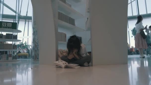 中国女孩坐在地板上看书 在著名的上海书店 上海图书馆 有趣的设计书店 — 图库视频影像