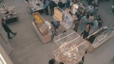 İnsanlar büyük, modern bir kitapçıda yürürken ve kitap alırken.