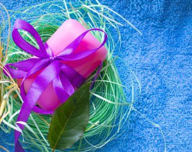 Pembe sabun, çok renkli saten kurdelelerle bağlanmış, ince renkli kağıt şeritlerle, mavi havluyla.