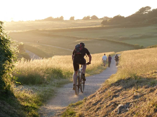 Güneş batmaya başladığında insanlar Şeytan 'ın Lezbiyeni' ne doğru yürüyor ve bisiklet sürüyor..