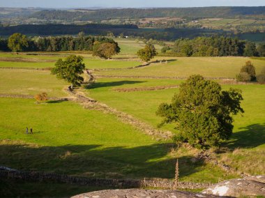 Derbyshire, Peak District 'te bir sonbahar akşamında güneş batarken Robin Hood' s Stride 'ın manzarası alçaktan uzanan taş duvarları ve Dokuz Taş' ın dik duran taşlarını alır..