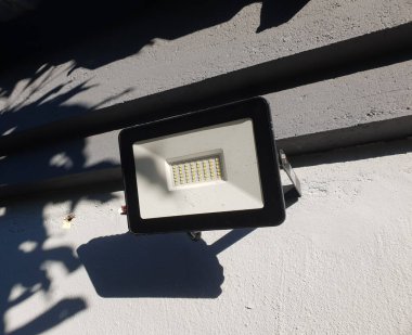 Siyah beyaz plastik çerçeveli sıvanmış ve boyanmış bir duvara projektör ışığı yerleştirildi.