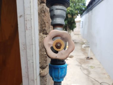 Suyun akışını kontrol etmek için kurulmuş yuvarlak bir musluk kabzasıyla su borusu bağlantısını kapat