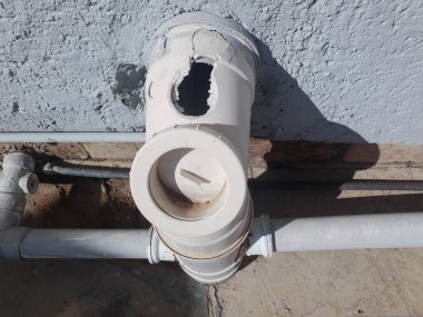 Kırık bir havalandırma borusuna yakın çekim ve dışarıda tuvalete bağlı bir delik.