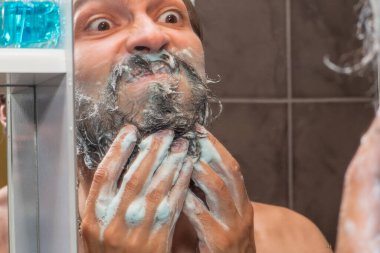 Sakal bakımı - bir adam sakalını sabun köpüğüyle yıkar