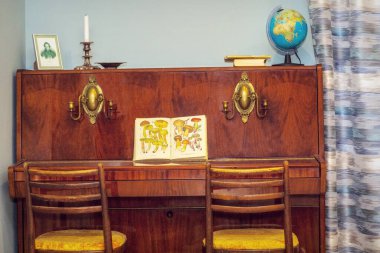 Eski bir piyano parçası, şamdanlar, bir küre, kitaplar, bir portre ve mantarlar hakkında bir kitap.