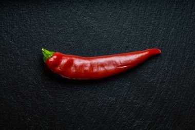 Siyah tahtada izole edilmiş bir kırmızı biber. Düz yatıyordu.