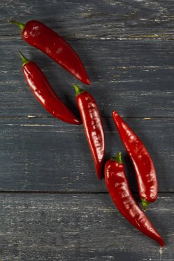 Ahşap masada beş kırmızı biber. Düz yatıyordu. 