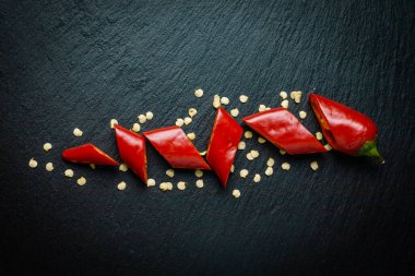 Bir biber dilimlenmiş ve tohumlar siyah eğimli tahtada izole edilmiş. Düz yatıyordu.