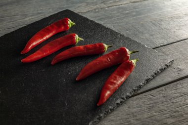 Siyah tahtada beş kırmızı biber. Düz yatıyordu.