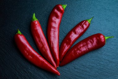 Siyah tahtada beş kırmızı biber. Düz yatıyordu.