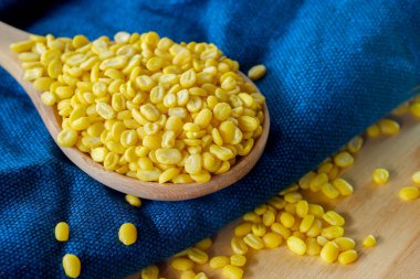 Mavi kumaş üzerinde, kaşık tahtasındaki Soyulmuş Mung fasulyesinin yakın çekimi. Sağlıklı gıda konsepti.