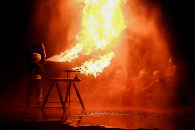 İtfaiyecilerden oluşan bir ekip gece alevli bir yangını söndürmek için alıştırma yapıyor..