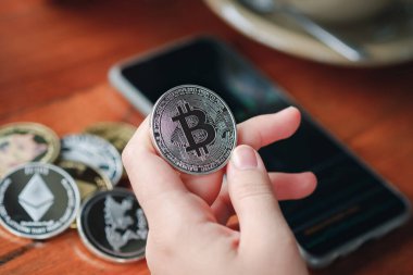 Maesot, Tayland - 13 Haziran 2021 Kafe 'de stok grafiğini gösteren Bitcoin ve akıllı telefonu tutan kadının eli. Şifreleme para sanal para kavramını kabul et.