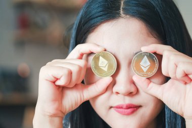 Maesot, Tayland - 13 Haziran 2021: iki gözünü de kapayan bir Ethereum sikke tutan kadın. Şifreleme para sanal para kavramını kabul et.