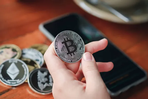 Maesot, Tayland - 13 Haziran 2021 Kafe 'de stok grafiğini gösteren Bitcoin ve akıllı telefonu tutan kadının eli. Şifreleme para sanal para kavramını kabul et.