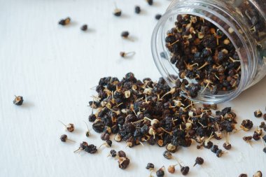 Beyaz arka planda şeffaf bir kavanozda siyah kurt üzümü ya da kara goji üzümü. Geleneksel Çin tıbbında sıklıkla kullanılan Çin bitkileri. Sağlık hizmeti kavramı.