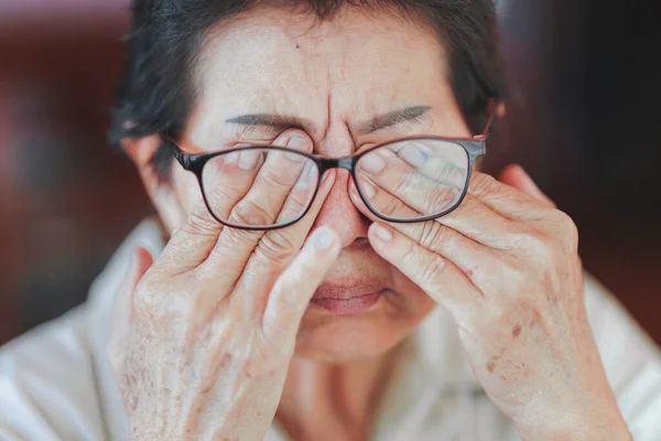 Elderly women rub their eyes or touch their eyes because of eye strain. Eye disease in the elderly.