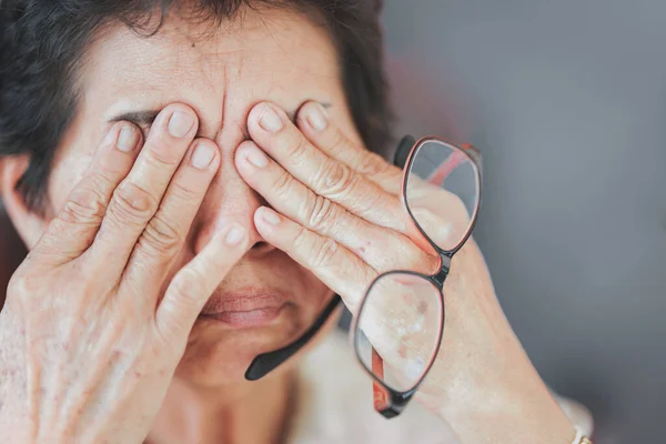 Elderly women rub their eyes or touch their eyes because of eye strain from using their eyes a lot.